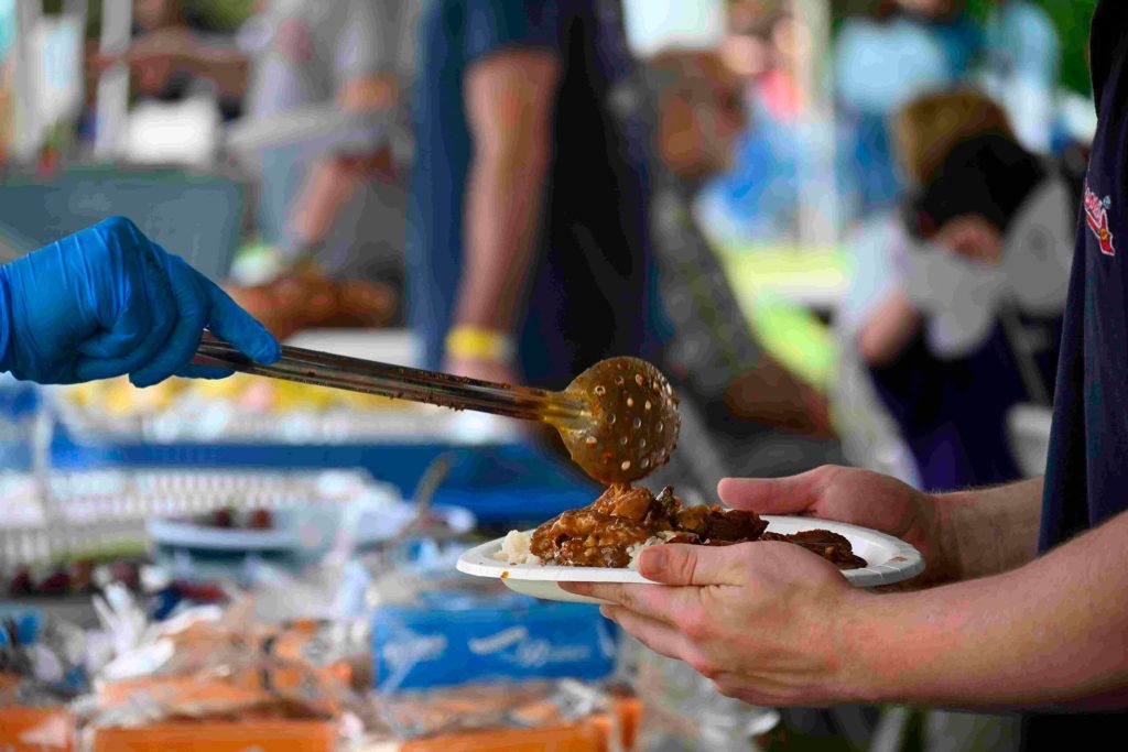 A close-up of a serving spoon loading food onto a plate