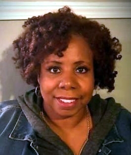 Headshot of a woman with curly hair looking at the camera