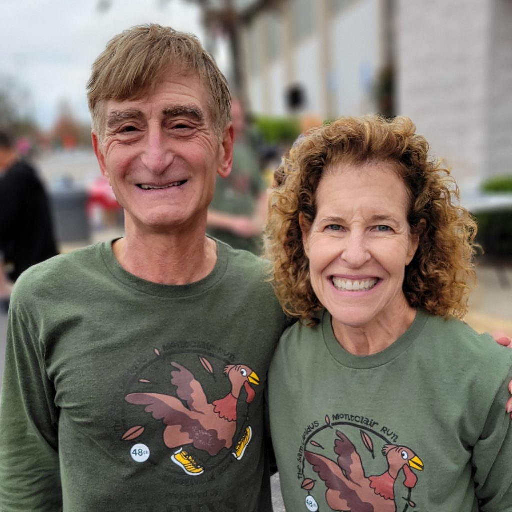 A man and woman both wearing the same olive green race t-shirt pose for the camera