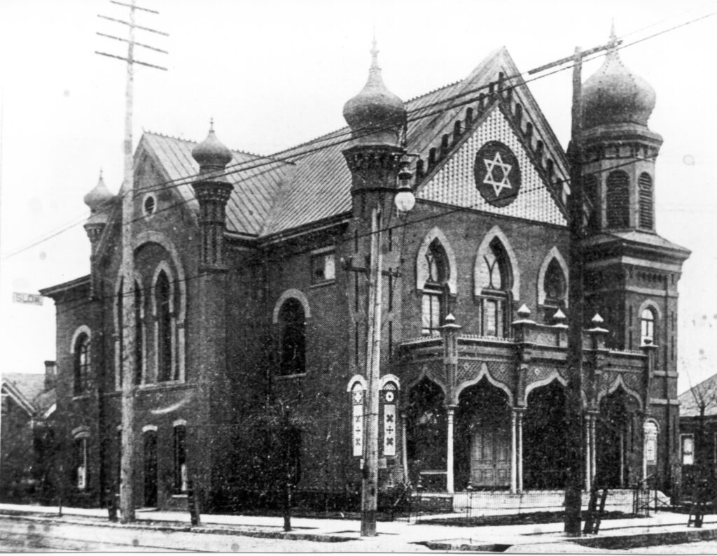Black and white photo of an old ornate Temple Emanu-El with a large Star of David inlaid at the top of the front facade and including four onion-topped minaret-type towers