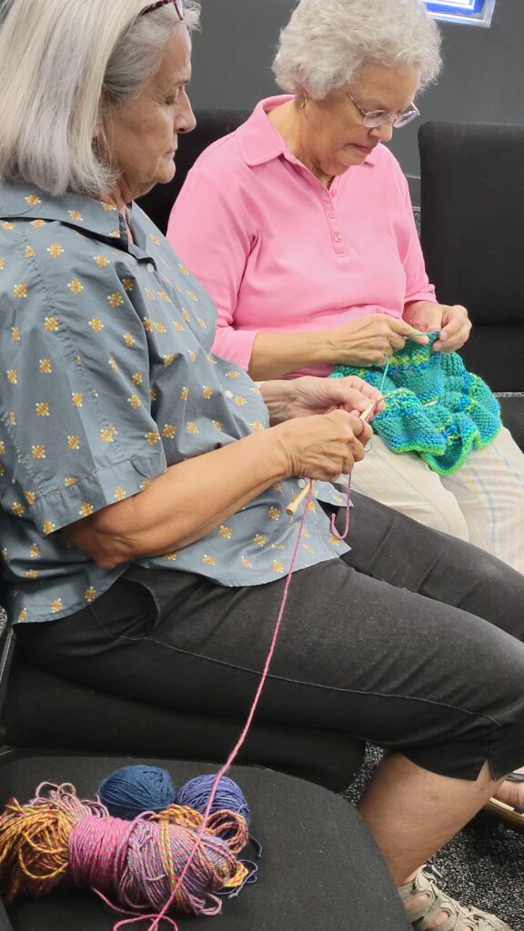 Two women knit during a weekly meeting of the Roz Feigelson Circle of Life Knitting Group gathering