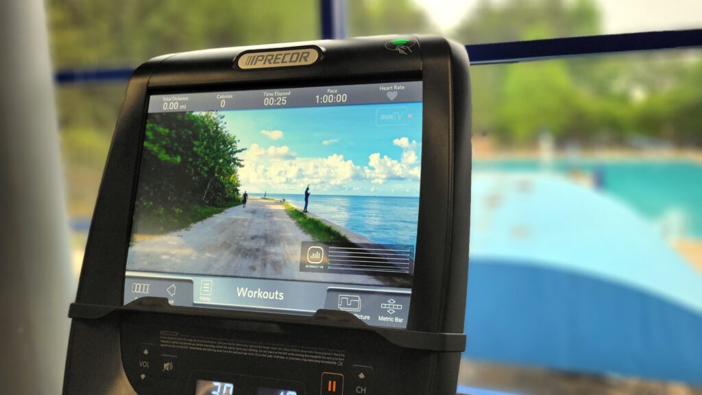 A treadmill display screen showing a road alongside a body of water