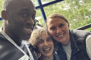 Three people take a close-up selfie in front of a window