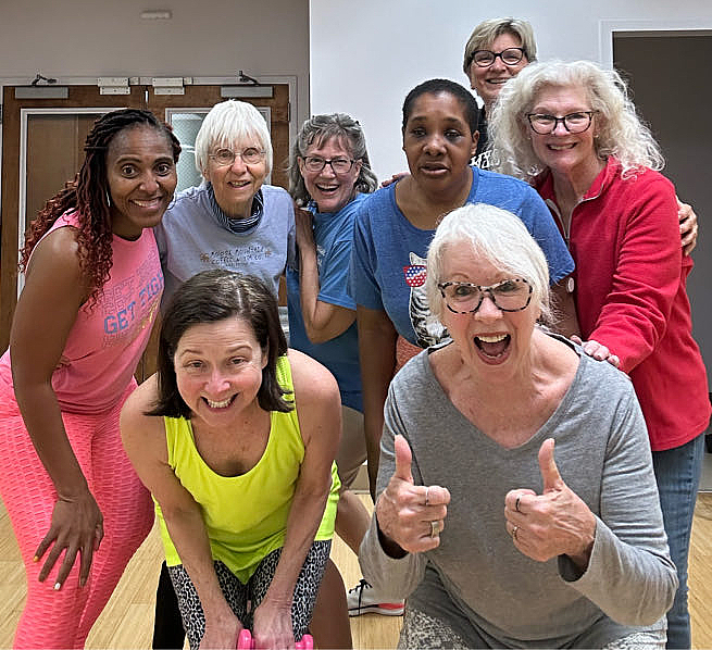 A group of eight women pose together after a group fitness class at The J