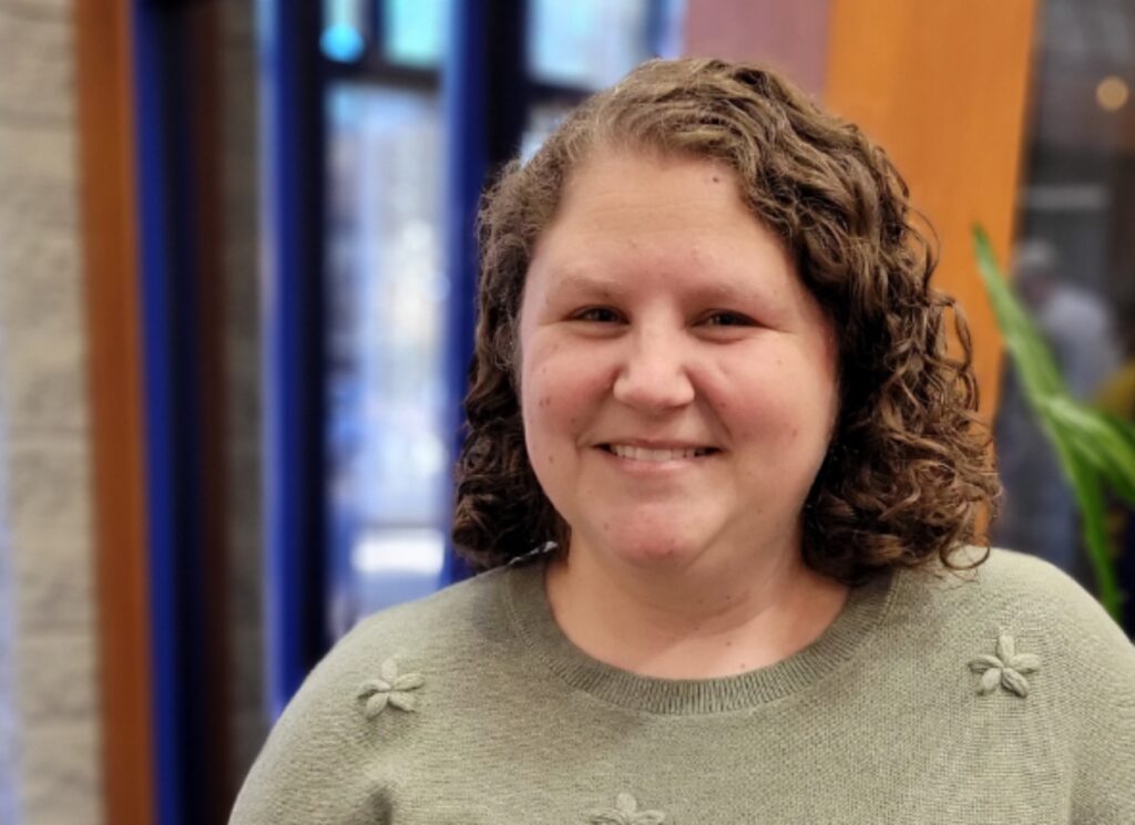 A smiling woman wearing a very light green sweater smiles for the camera