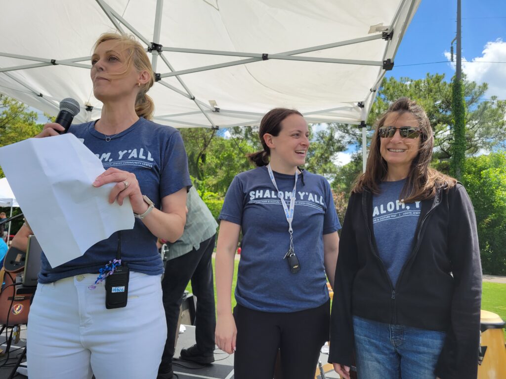 Executive Director Brooke Bowles stands on a stage with staff member Katie Hausman and Betty Habshey, organizer of the first Food Fest a quarter century ago