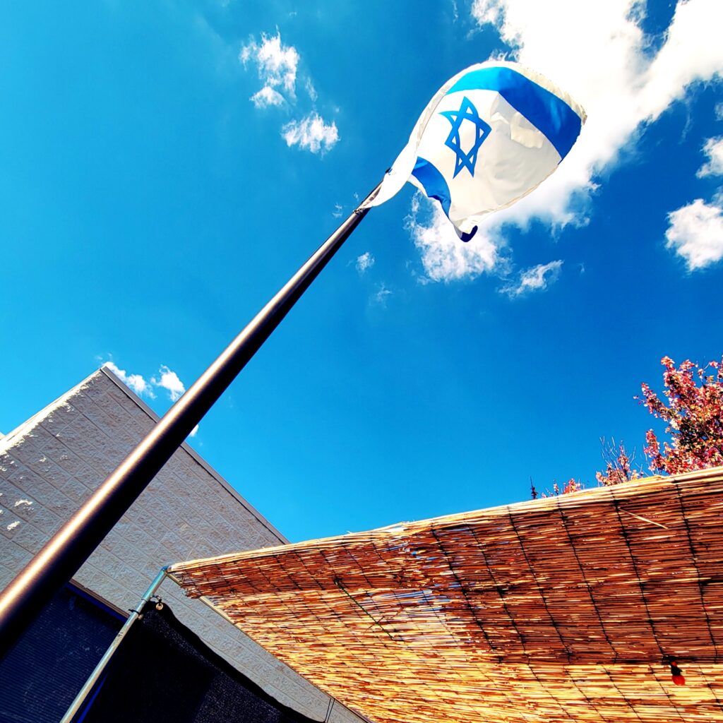 The Israeli flag flies in a blue sky above The J's sukkot.