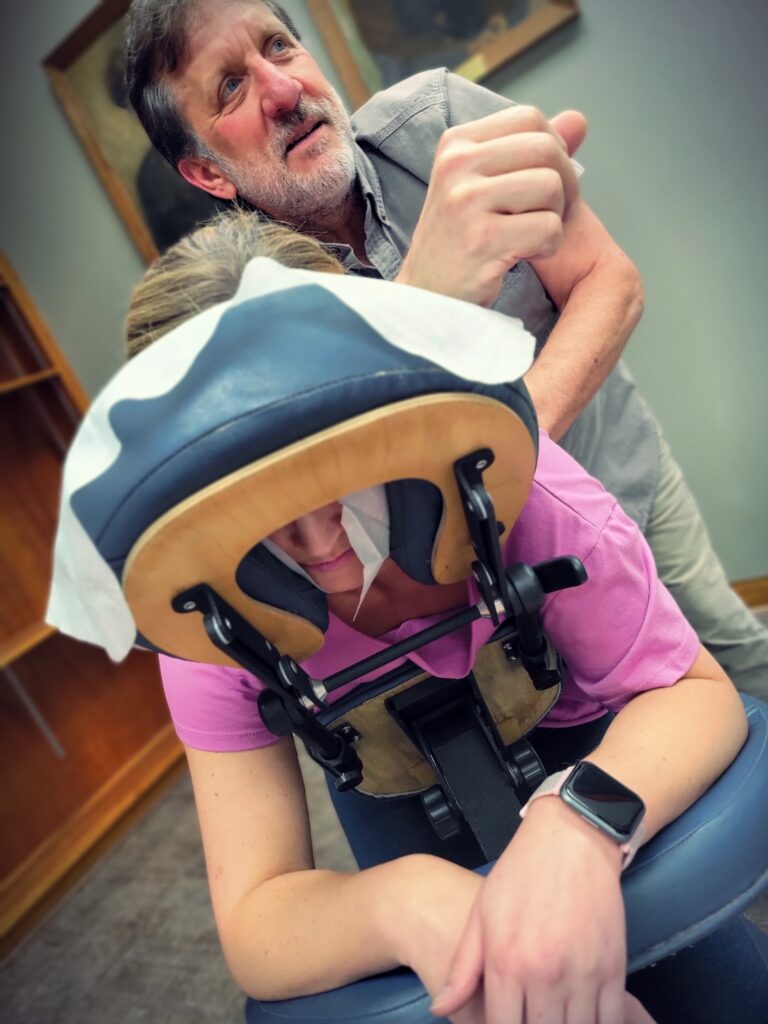 A masseur works on a woman in a massage chair