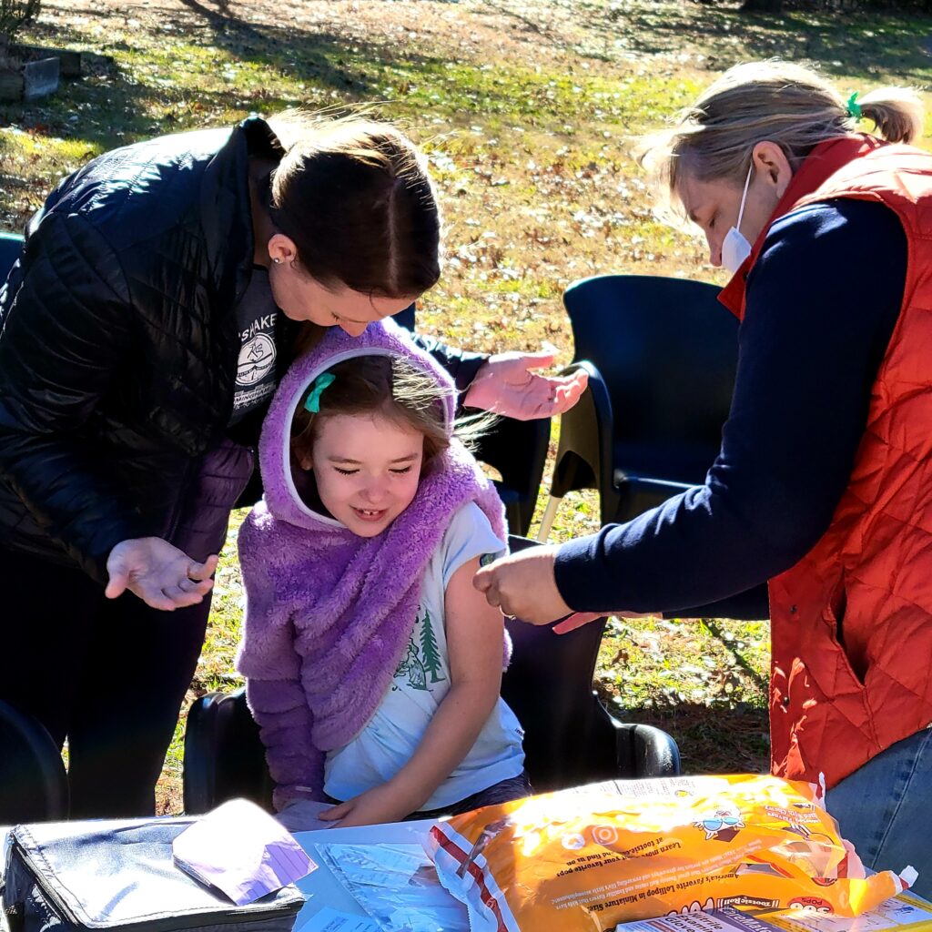 A seated young girl gets her Covid vaccination at The J's outdoor vaccine clinic held in December 2021