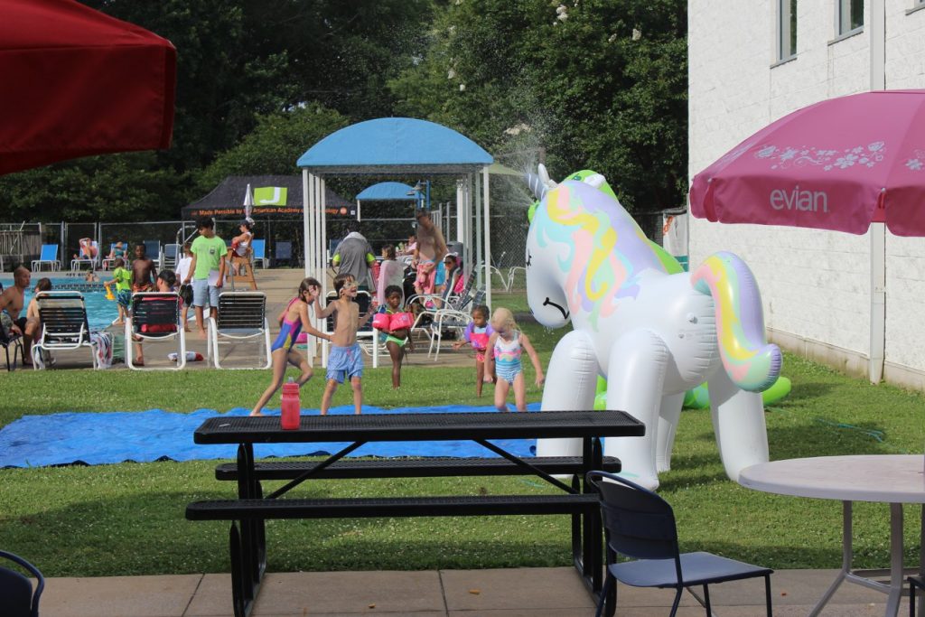 A group of children standing in front of an inflatable unicorn sprinkler