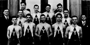 Eleven men and their two coaches pose in uniform after a basketball game in the early 1930s