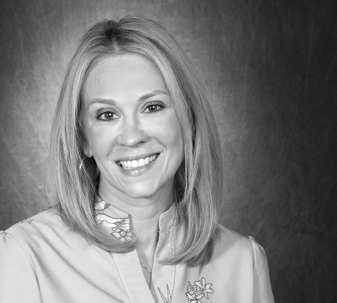 Black and white photo of a woman seated in a studio in shoulder-length blond hair