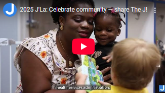 A woman holding a child crouches down while chatting with another child whose back is to the camera