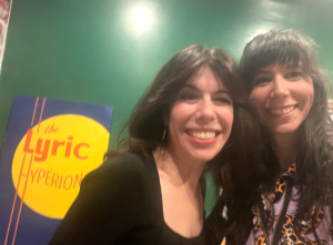 Two women take a selfie in front of a Lyric Hyperion sign
