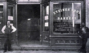 Two men stand in front of a bank in this black and white photo