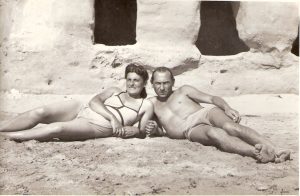 Two people in bathing suits sprawl next to each other in a black and white photo from the 1940s.