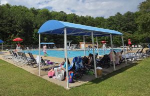 People lounge under a canopy by the Levite JCC pool