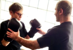 A woman and a man spar in front of a glass block wall