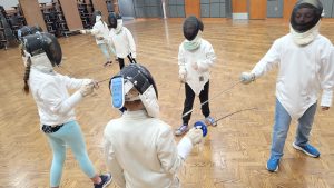Kids practice fencing in the auditorium
