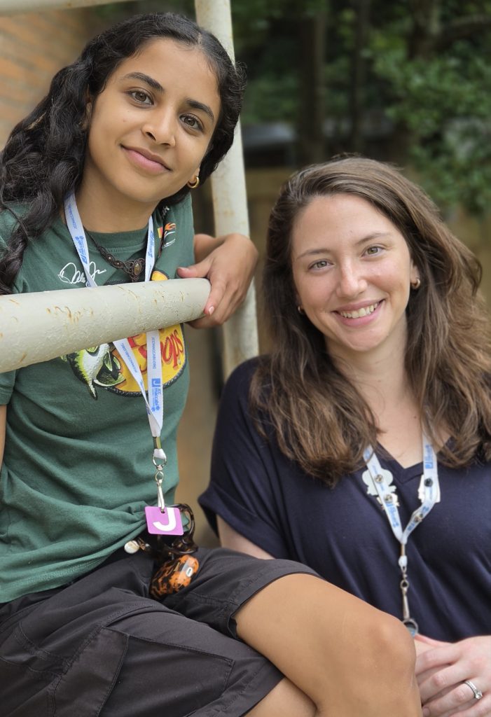Two women pose together outside by a stairway.