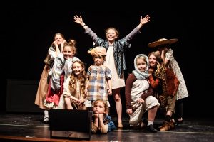 A group of young thespians strikes a dramatic pose while on stage.